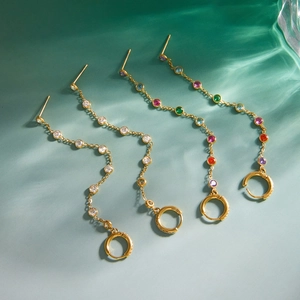 Detail of gold dangle earrings with colorful rhinestones and elegant fringe tassels