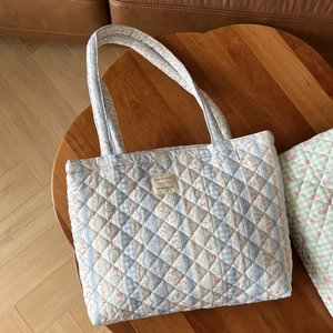 Detailed close-up of quilted floral tote bag with blue checkered patterns and woven label