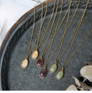Flat lay of multiple irregular green aventurine pendants on 18K gold plated chains