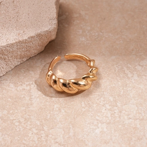 Detailed shot of golden twisted metal ring on a textured beige stone background