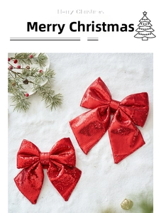 Close-up of sparkling red sequin Christmas bows on snowy background with pine branches