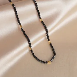 Detail of 14K gold beads and black faceted stones on champagne satin background