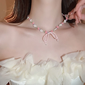 Close-up of sweet beaded necklace featuring pink bow pendant and flower motifs on neck