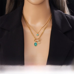 Detail of layered gold stainless steel necklace with Tree of Life and turquoise charms