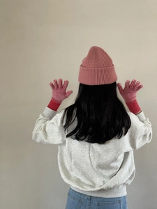 Primer plano de gorro de punto rosa y guantes térmicos a rayas rojas y blancas