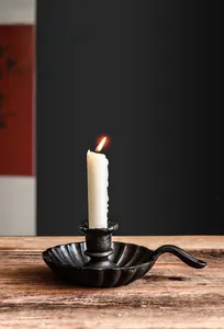 Macro detail of a vintage cast iron candle holder with handle and burning white candle