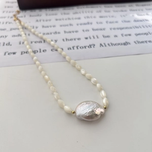 Macro view of baroque pearl necklace featuring large irregular center pearl and gold accents