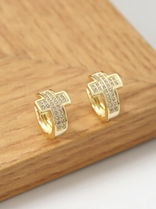 Macro shot of gold cross hoop earrings with pave cubic zirconia on a wooden block