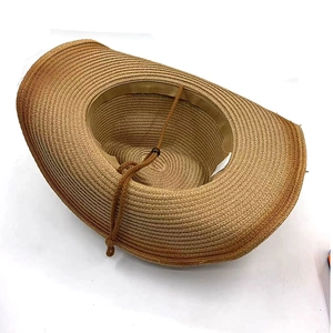 Detail of light brown straw cowboy hat showing woven texture and adjustable chin strap