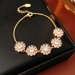 Macro detail of vintage gold flower bracelet with clear zircons on black jewelry box