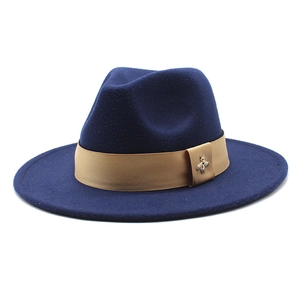 Detail of dark blue fedora hat featuring light brown silk band and golden bee charm