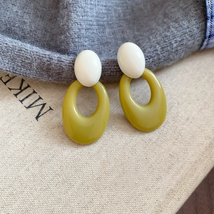 Detailed shot of retro oval acrylic drop earrings in white and olive green resin
