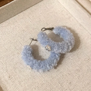 Macro shot of light blue flocked round earrings with metallic silver snowflake charms