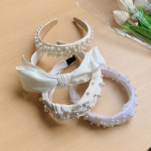 Detail view of Korean style pearl and bow headbands on a wooden table with tulips