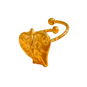 Detailed view of golden irregular heart ring with hammered texture and floral engraving
