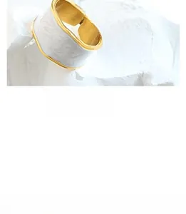 Close-up of a wide gold-plated open ring with an elegant white marble enamel texture