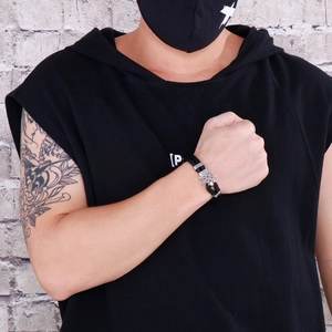 Close-up of men's double-layer black leather bracelet with a silver steel rudder charm