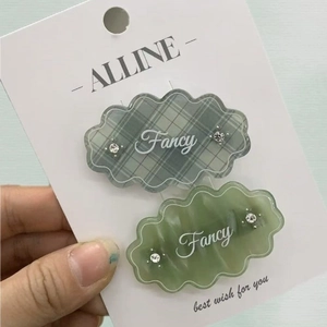 Detail of green plaid and marble hair clips with crystal accents and Fancy lettering
