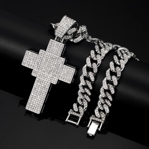Detailed close-up of a silver-toned iced-out Cuban link necklace with a cross pendant