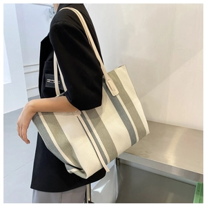 Close-up of a large canvas tote bag with olive green and beige vertical stripes for women
