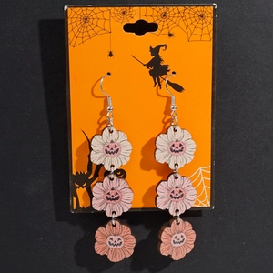 Macro view of wooden pumpkin drop earrings with tiered gradient colors and face patterns