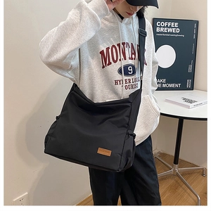 Große schwarze Canvas Umhängetasche von einem Modell in Freizeitkleidung getragen
