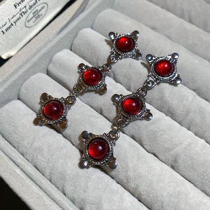 Detail of dark gothic silver earrings featuring deep red round stones and baroque filigree
