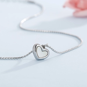 Détail macro du pendentif cœur argenté avec incrustation nacre blanche sur chaîne serpent