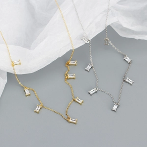 Detail of silver and gold link necklaces with rectangular clear zircon stone pendants