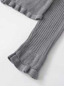 Detail of grey ribbed knit fabric with lettuce edge cuffs and pointelle cutout design