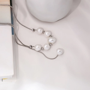 Detail of silver snake chain necklace featuring elegant pearls and metallic spheres