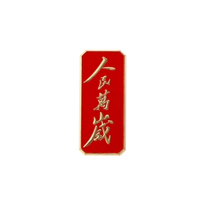 Detail of red rectangular enamel pin with gold calligraphy saying Long Live the People