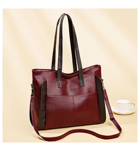 Detail of burgundy PU leather tote bag with brown straps and adjustable shoulder strap