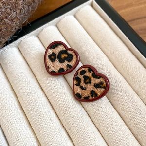 Close-up of heart-shaped leopard print earrings in burgundy frame on velvet jewelry box