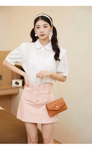 Detail of pink denim mini skirt with heart pocket and white lace ruffle shirt