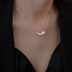 Elegant four-pearl gradient necklace on silver chain worn with a black blazer suit