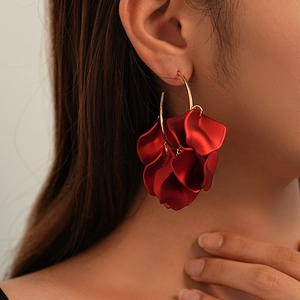 Detailed view of red acrylic floral petals layered on a large golden hoop earring