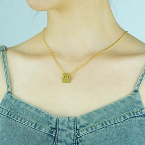 Detailed view of gold square Aries constellation pendant necklace on model neck