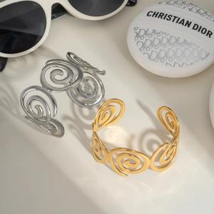 Detailed close-up of spiral textured open bangles in polished gold and silver steel finish