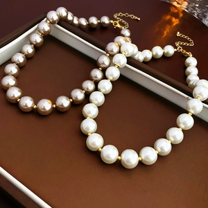 Close-up of baroque pearl necklaces in cream white and champagne gold with gold lobster clasp