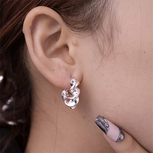 Close-up of polished silver U-shaped twisted hoop earrings on a female model