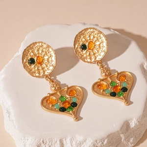 Macro detail of vintage heart drop earrings with colorful stones on a white stone base