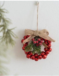 Detail of red metal Christmas bells with burlap bow and pine needles hanging on wall