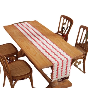 Cotton table runner with red geometric patterns and tassels on a wooden dining table