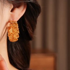 Detail of 24k gold-plated hoop earring with woven mesh texture on a female model