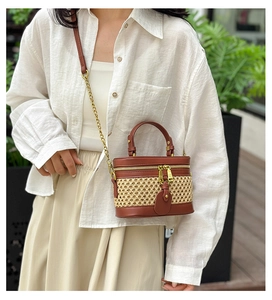 Close-up of woven straw and brown leather bucket bag with metal chain strap