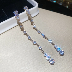 Close-up of golden long tassel earrings with sparkling teardrop zircon stones