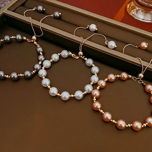 Detailed shot of adjustable pearl bracelets in white, grey and pink on leather display