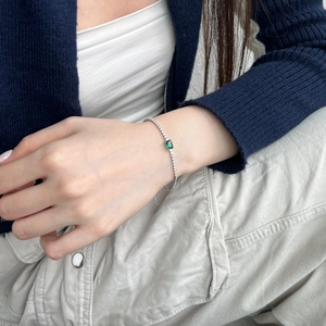 Detailed close-up of S925 silver tennis bracelet with emerald green stone on a wrist