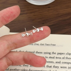 Minimalist 925 sterling silver candy-shaped stud earrings shown for scale on a finger